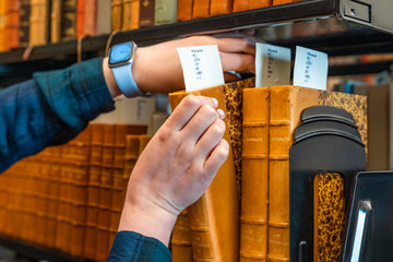someone grabbing a book off a bookshelf